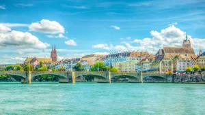 Skyline von Basel: Malerischer Blick auf den Rhein, historische Gebäude und moderne Architektur bei strahlend blauem Himmel.