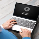 Ein MacBook, auf dem Monitor wird das typische Einstellung Symbol (graues Zahnrad) angezeigt. Symbolisiert werden soll Datenrettutng bei macOS.